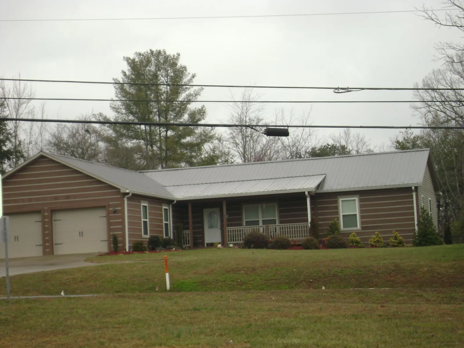 Gray metal roof on a log sided ranch home with a front porch in Ashburn