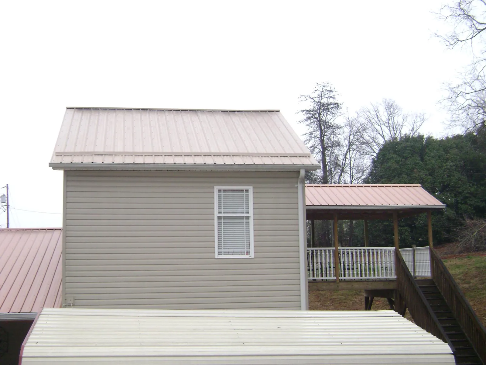 Tan metal roofs on a two story addition and attached porch, from a Roof Replacement job in Ashburn